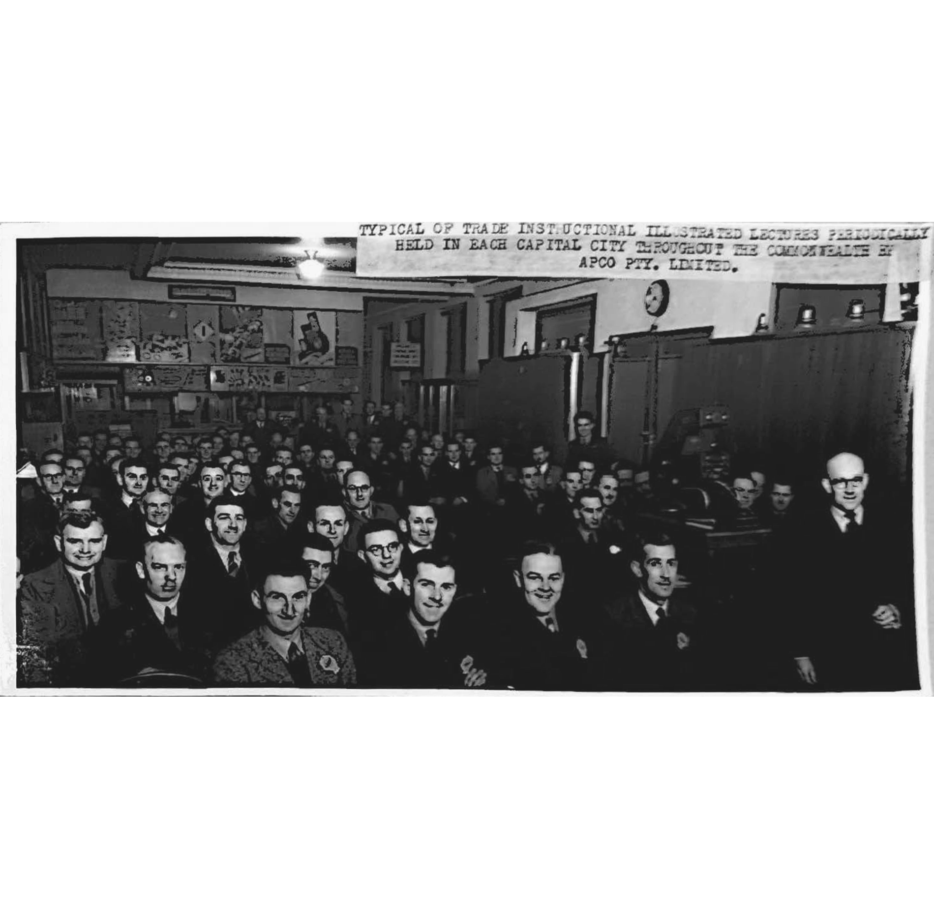 A black and white photograph of men in suits sitting in a lecture hall.